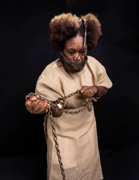 Portrait of a black woman in chains with an iron mask on her face representing the slave Anastacia. Old and rusty chains. Slavery in Brazil.