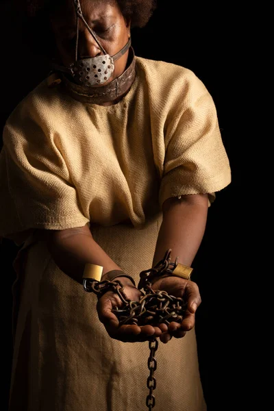 Portrait of a black woman in chains and with an iron mask on her face holding chains. Slave Anastacia. Slavery in Brazil.