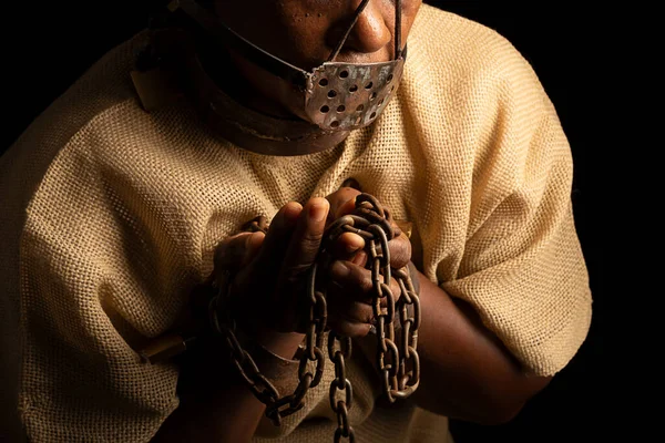 Close-up portrait of a black woman with chains on her hands and an iron mask on her face. Slave Anastacia. Slavery in Brazil.