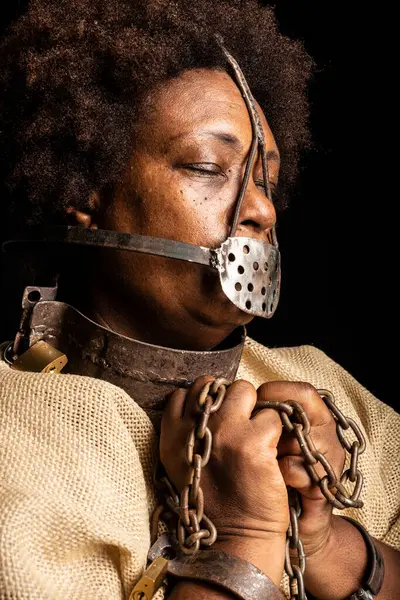 Portrait of a black woman with chains on her hands and an iron mask on her face representing the slave Anastacia. Slavery in Brazil.
