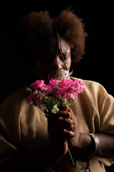 Portrait of a black woman with chains on her hands and an iron mask on her face holding a bunch of flowers. Slave Anastacia. Slavery in Brazil.