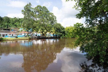 Valenca, Bahia, Brezilya - 10 Ocak 2023: Bitkiler, ağaçlar ve ticari binalarla çevrili Una Nehri manzarası. Brezilya 'nın Bahia eyaletindeki Valenca turistik kenti. gezinilebilir nehir.