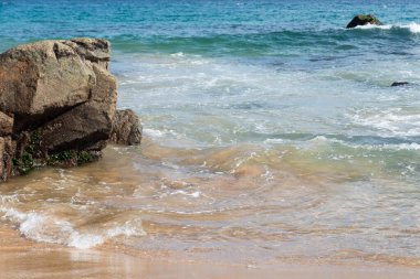 Deniz dalgaları sahilin siyah kayalarına çarpıyor. Rahatlama hissi..