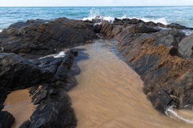Sahildeki kayalara vuran dalgalar şeklinde deniz suyu. Özgür ve sağlıklı doğa.