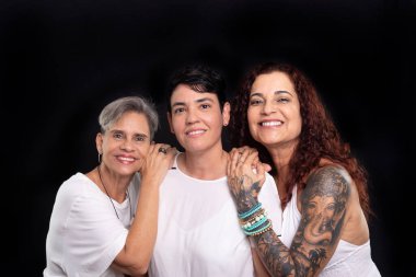 Üç kadının stüdyo fotoğrafı, lezbiyenler, mutlu ve özgür bir şekilde kameraya bakıyorlar. Siyah arkaplanda izole.