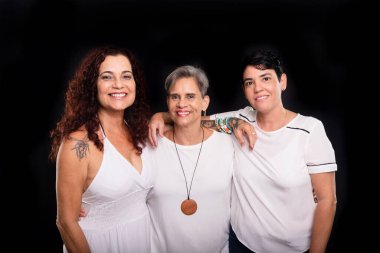 Üç kadının stüdyo fotoğrafı, lezbiyenler, mutlu ve özgür bir şekilde kameraya bakıyorlar. Siyah arkaplanda izole.