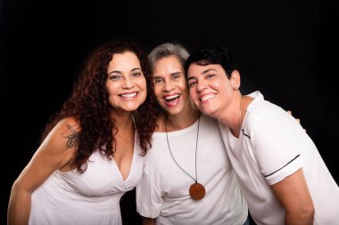 Üç kadının stüdyo fotoğrafı, lezbiyenler, mutlu ve özgür bir şekilde kameraya bakıyorlar. Siyah arkaplanda izole.