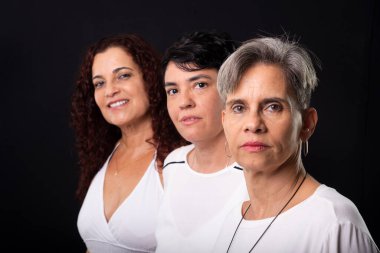 Üç güzel kadının portresi, lezbiyenler, müzisyen arkadaşlar ve kameraya poz verirken mutlu olmak. Siyah arkaplana karşı stüdyo görüntüsü.