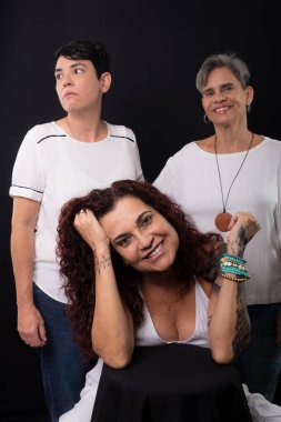 Üç güzel kadın, bir oturma ve iki ayakta, müzisyen lezbiyenler arkadaşlar ve stüdyoda siyah arka planda mutlular..