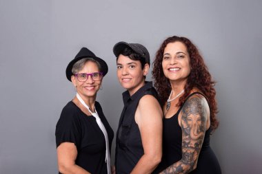 Üç güzel kadın, arkadaşlar, fotoğraf için poz veren bir müzik grubunun üyeleri. Gri arkaplanda izole.