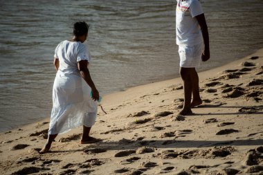 Salvador, Bahia, Brezilya - 12 Aralık 2021: Candomble üyeleri Rio Vermelho sahilinde yürürken görüldü..