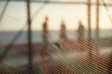 İnsan silueti, bir güvenlik ağı üzerinden, öğleden sonra bir plajın kenarında yürüyor. Soyut fotoğrafçılık kavramı.