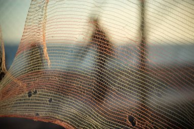 İnsan silueti, bir güvenlik ağı üzerinden, öğleden sonra bir plajın kenarında yürüyor. Soyut fotoğrafçılık kavramı.