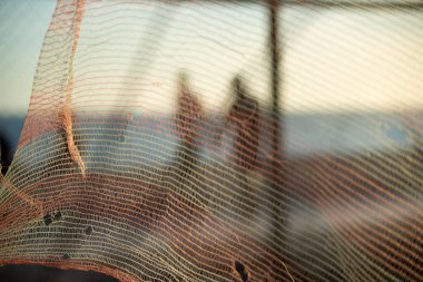 İnsan silueti, bir güvenlik ağı üzerinden, öğleden sonra bir plajın kenarında yürüyor. Soyut fotoğrafçılık kavramı.