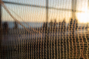 İnsan silueti, bir güvenlik ağı üzerinden, öğleden sonra bir plajın kenarında yürüyor. Soyut fotoğrafçılık kavramı.