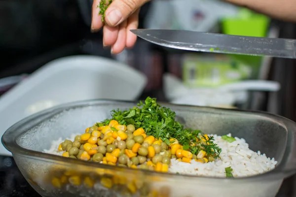Salad with peas, corn and coriander being prepared in a glass bowl. Healthy food.