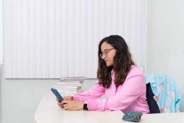Ofisinde pembe kıyafetler giyen, oturan, cep telefonundaki randevularına bakan bir psikopat portresi. Okul performansına yardımcı oluyor. Akıl sağlığına dikkat et..
