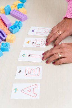 Alfabedeki harfleri gösteren bir psiko-pedagogun eli. Eğitimsel yardım. Ruh sağlığı hizmetleri.