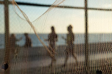 Siluet ve yaya figürleri öğleden sonra bir plajın kenarında yürüyorlar. Soyut fotoğrafçılık kavramı.