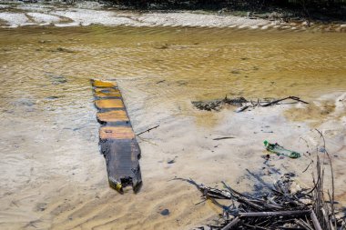 Sarı bir nehirde yüzen dallar ve odun parçaları. Ortam değişiyor.