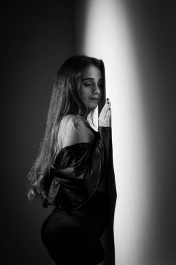 Sarı saçlı, yüzü ve eli beyaz bir duvara dayalı siyah beyaz bir kadın portresi. Stüdyoda çekilmiş bir resim..