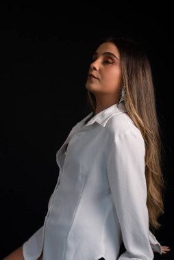 Beyaz bluz ve siyah şort giyen sarı saçlı güzel beyaz bir kadının stüdyo portresi. Siyah bir arkaplan ile izole edilmiş.