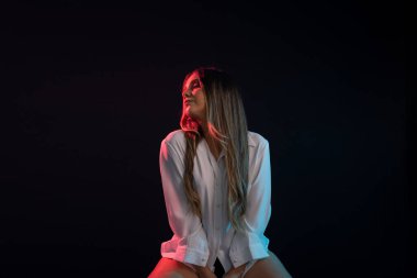 Uzun saçlı, fotoğrafçılık için poz veren güzel beyaz bir kadın. Stüdyoda siyah arkaplanlı fotoğraf.