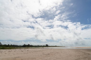 Issız bir sahilde beyaz kum, mavi gökyüzü ve arka planda bulutlar. Korunmuş çevre. Valenca, Brezilya
