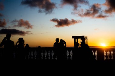 Salvador, Bahia, Brezilya - 23 Nisan 2022: Salvador, Bahia 'daki Barra mahallesinde gün batımının keyfini çıkaran bir grup insanın silueti.