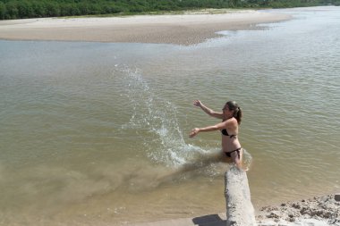 Nehirde bikinili güzel bir kadın havaya su fırlatıyor. Tatilde olan ve seyahat eden biri. Valenca, Brezilya 'daki Taquari Plajı.