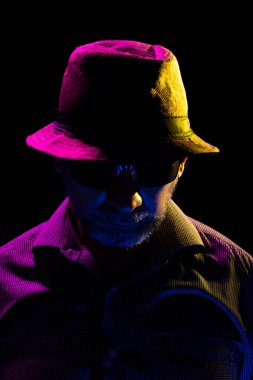 Şapkalı ve güneş gözlüklü gizemli adam. Karanlık stüdyoda portre.