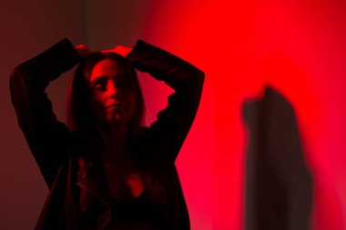 Siyah elbiseler giyen, eli başının üzerinde kırmızı resme poz veren güzel genç bir manken. Stüdyo resmi