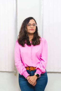 Krem renkli bir duvarın önünde duran güzel bir kadın fotoğraf için poz veriyor. Ruh sağlığıyla ilgilenen psiko-pedagog. Eğitim yardımı