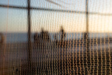 Bisikletçilerin silueti ve gün batımına karşı sahilde yürüyen insanlar. Fiziksel egzersizler ve zihnin rahatlaması..