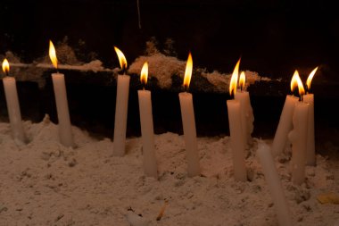 Mumlar dua etmek için karanlık bir yerde yanıyor. Dini istek konsepti. sarı mum ışığı