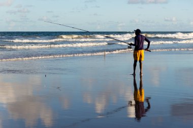 Salvador, Bahia, Brezilya - 26 Nisan 2019: Balıkçı, Bahia 'nın Salvador kentindeki Jaguaribe sahilinde elinde bir oltayla görüldü..