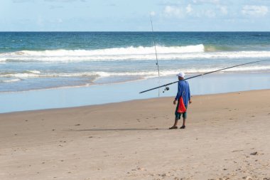 Salvador, Bahia, Brezilya - 26 Nisan 2019: Balıkçı, Bahia 'nın Salvador kentindeki Jaguaribe sahilinde elinde bir oltayla görüldü..