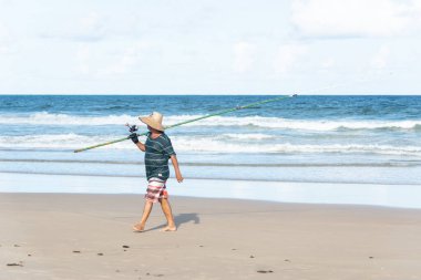 Salvador, Bahia, Brezilya - 26 Nisan 2019: Balıkçı, Bahia 'nın Salvador kentindeki Jaguaribe sahilinde elinde bir oltayla görüldü..