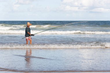 Salvador, Bahia, Brezilya - 26 Nisan 2019: Balıkçı, Bahia 'nın Salvador kentindeki Jaguaribe sahilinde elinde bir oltayla görüldü..
