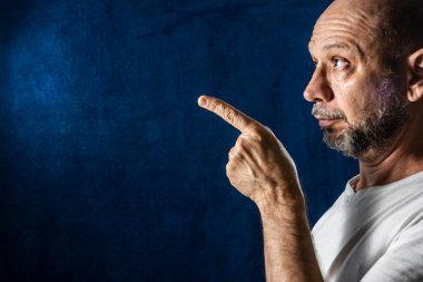 Kafası karışmış, yan tarafı işaret ediyor. Üzgün insanlar. mavi arkaplan.