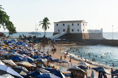 Salvador, Bahia, Brezilya - 21 Ekim 2023: Salvador, Bahia 'da güneş ve denizde yıkanan insanlarla dolu Porto da Barra manzarası.