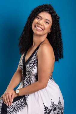 Kıvırcık saçlı, gülümseyen güzel bir kadın. Mavi arkaplanda izole.