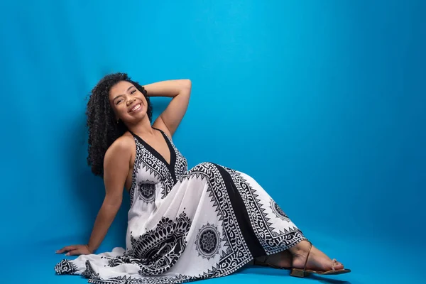 stock image Portrait of beautiful woman with curly hair sitting on the floor. Isolated on blue background.