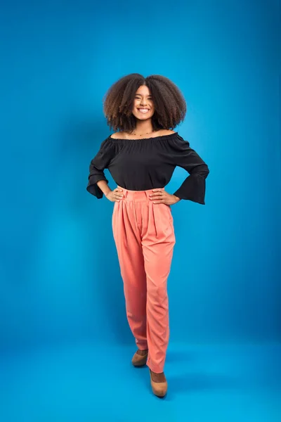 stock image Beautiful young woman with black power hair, dressed formally. Isolated on blue background.