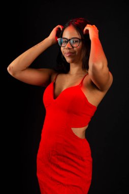 Eli saçı olan, gözlüklü ve kırmızı elbiseli güzel bir kadın. Siyah arkaplanda izole.