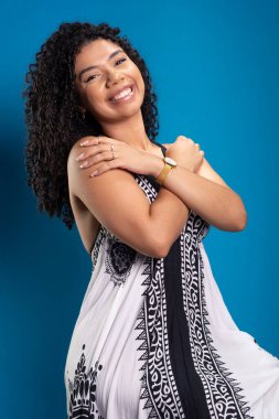 Kıvırcık saçlı, fotoğraf için poz veren güzel bir genç kadın. Mavi arkaplanda izole.