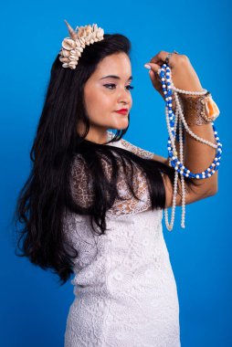 Kafasında deniz kabuğu tacı olan güzel, siyah saçlı kadın inci kolyelere bakıyor. Iemanja Özelleştirmesi.