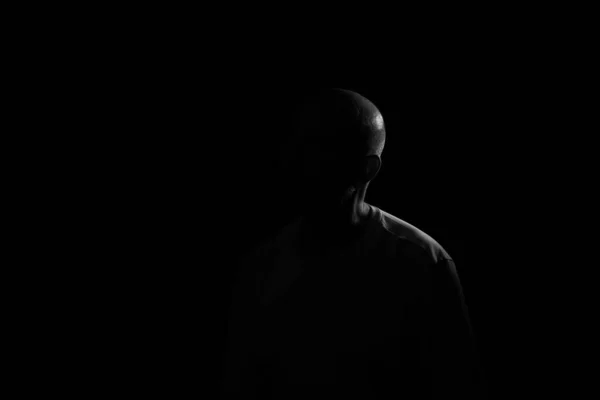 Low light portrait of bearded, bald man. Dark background