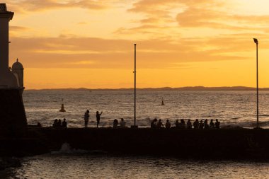 İnsanların silueti, gün batımında, Salvador, Bahia 'daki Porto da Barra rıhtımında.