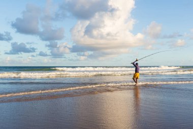 Salvador, Bahia, Brezilya - 26 Nisan 2019: Balıkçı, Bahia 'nın Salvador kentindeki Jaguaribe sahilinde elinde bir oltayla görüldü..